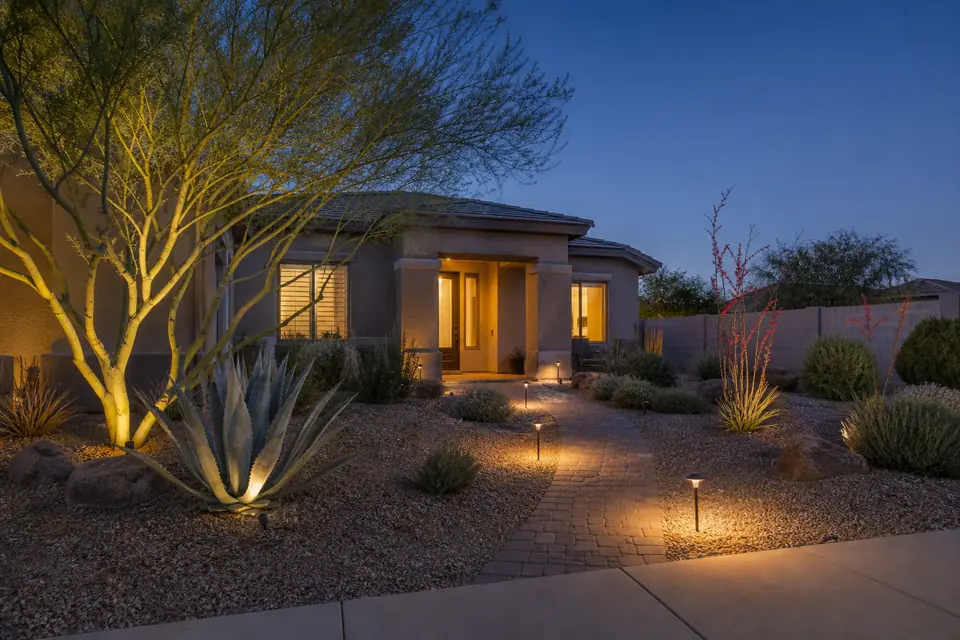 Warm low-voltage landscape lighting along a Chandler desert front yard at dusk