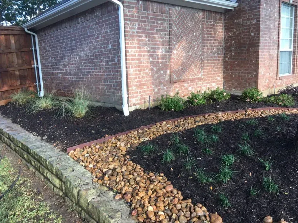 Finished planted bed with low wall and stone drainage channel